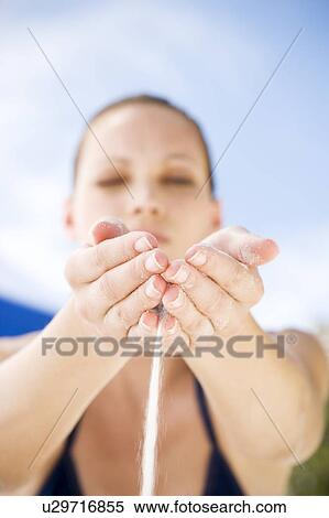 Stock Photography - A young woman letting sand run through her fingers. Fotosearch