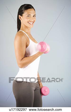 Stock Photo - A young woman lifting weights. Fotosearch