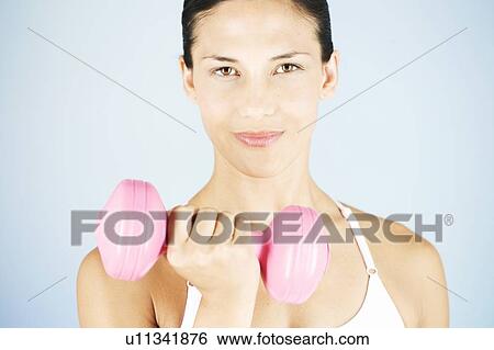 Stock Photograph - A young woman lifting weights. Fotosearch