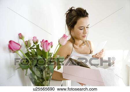 Stock Image - A young woman looking at old photographs. Fotosearch