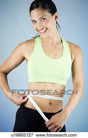 Stock Photo - A young woman measuring her waist. Fotosearch