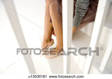 Stock Image - A young woman putting on shoes. Fotosearch