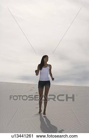 Stock Image - A young woman running in the desert. Fotosearch