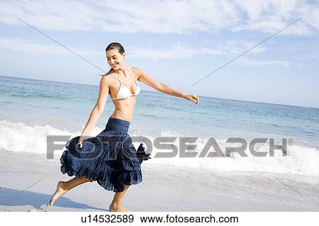 Stock Photo - A young woman running on the beach . Fotosearch