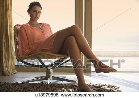 Stock Photograph - A young woman sitting in a chair. Fotosearch