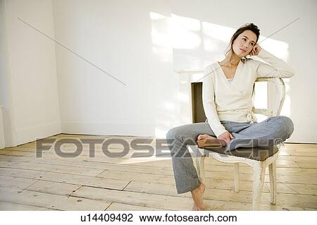 A young woman sitting on a chair View Large Photo Image Stock Image - A young woman sitting on a chair. Fotosearch