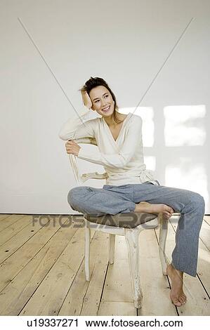 Stock Image - A young woman sitting on a chair. Fotosearch
