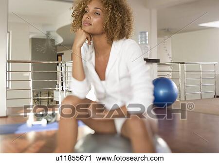 A young woman sitting on an exercise ball View Large Photo Image Stock Image - A young woman sitting on an exercise ball. Fotosearch