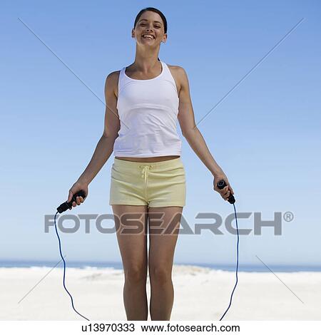 Stock Image - A young woman skipping on a beach. Fotosearch