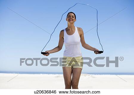 Stock Photograph - A young woman skipping on a beach. Fotosearch