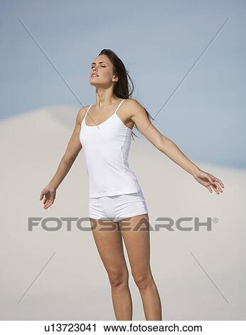 Stock Image - A young woman standing in the desert. Fotosearch