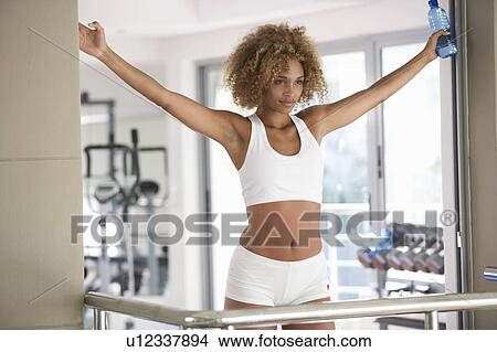 Picture - A young woman stretching at the gym. Fotosearch