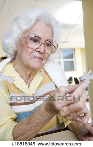 Stock Photograph - An elderly woman completing a jigsaw. Fotosearch