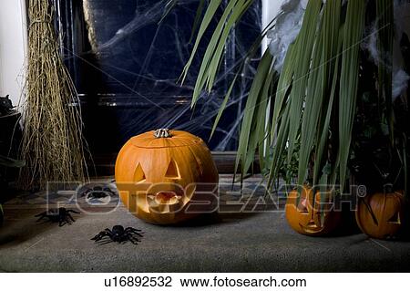 Stock Image - Atmospheric Hallowe'en scene - pumpkin, broomstick and spiders . Fotosearch
