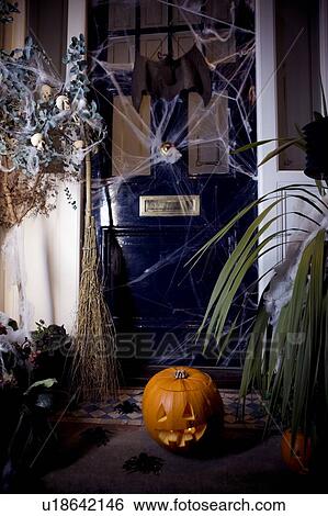 Stock Photograph - Atmospheric Hallowe'en scene - pumpkin, broomstick and cobwebs by the door. Fotosearch