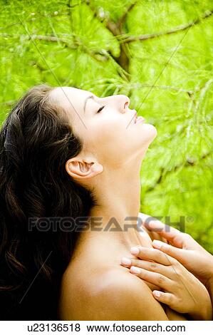 Stock Photo - Beauty portrait of a woman in a tropical setting touching her neck.. Fotosearch