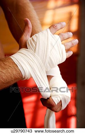 Stock Image - Boxer binding up hands with padding bandages. Fotosearch