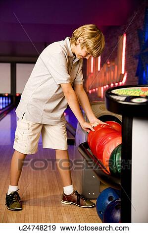Stock Photo - Boy in a bowling alley choosing a bowling ball. Fotosearch