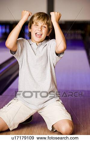 Stock Photo - Boy in a bowling alley making victory salute. Fotosearch