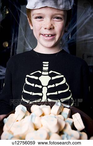 Boy in a skeleton costume at a Hallowe'en party, holding a tray of sweets View Large Photo Image Stock Photo - Boy in a skeleton costume at a Hallowe'en party, holding a tray of sweets . Fotosearch