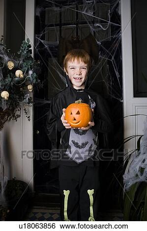 Boy in a skeleton costume at Hallowe'en, holding a pumpkin with a carved face View Large Photo Image Stock Photograph - Boy in a skeleton costume at Hallowe'en, holding a pumpkin with a carved face. Fotosearch