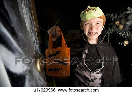 Boy in costume at a Hallowe'en party, holding an orange party bag View Large Photo Image Stock Photograph - Boy in costume at a Hallowe'en party, holding an orange party bag. Fotosearch