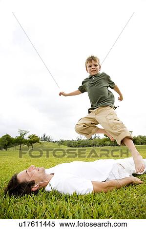 Boy jumping over man lying on the grass View Large Photo Image Stock Photography - Boy jumping over man lying on the grass. Fotosearch
