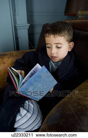 Stock Image - boy reading book in his pajamas. Fotosearch