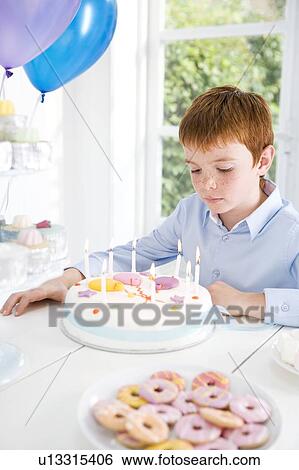 Stock Photograph - boy sitting at birthday tea table. Fotosearch