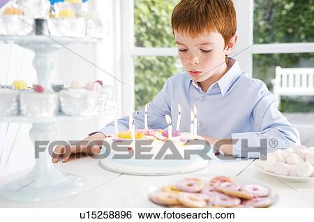 Stock Photograph - boy sitting at birthday tea table. Fotosearch