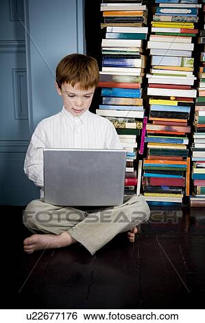 Stock Photograph - boy sitting on floor working on laptop computer. Fotosearch