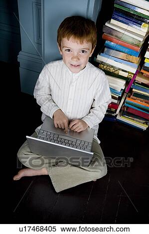 Stock Photography - boy sitting on floor working on laptop computer. Fotosearch