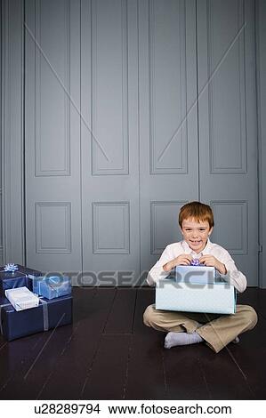 Picture - boy sitting on the floor with presents on his lap. Fotosearch