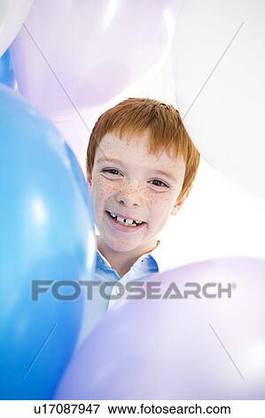 Stock Photo - boy's face smiling framed by balloons. Fotosearch