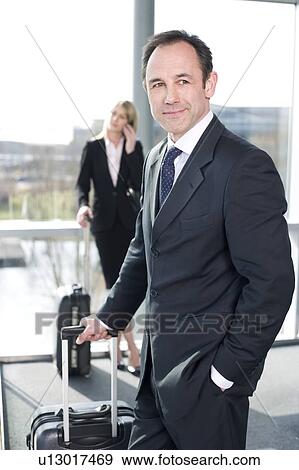 Stock Photo - Businessman and businesswoman traveling, waiting in airport or station. Fotosearch