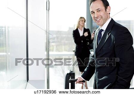 Stock Photograph - Businessman and businesswoman traveling, waiting in airport or station. Fotosearch