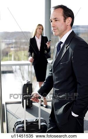 Stock Photography - Businessman and businesswoman traveling, waiting in airport or station. Fotosearch