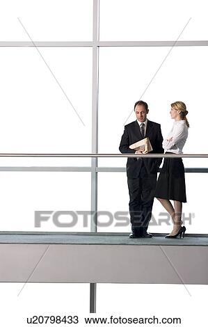 Stock Image - Businessman and woman talking in modern office building. Fotosearch