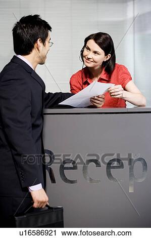 Stock Image - Businessman being greeted at office reception. Fotosearch