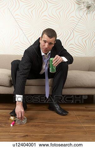 Stock Image - Businessman drinking a can of lager and smoking. Fotosearch