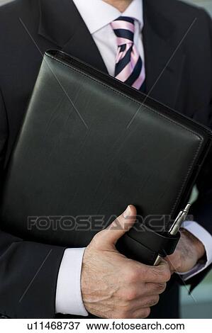 Stock Photo - Businessman holding a leather case with briefing papers. Fotosearch