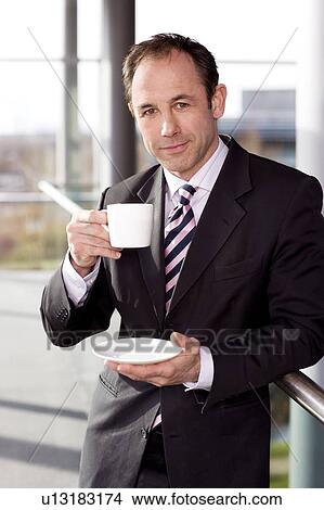 Businessman in office drinking a cup of coffee View Large Photo Image Picture - Businessman in office drinking a cup of coffee. Fotosearch