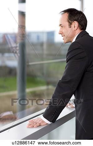 Businessman looking out of office window View Large Photo Image Stock Photo - Businessman looking out of office window. Fotosearch
