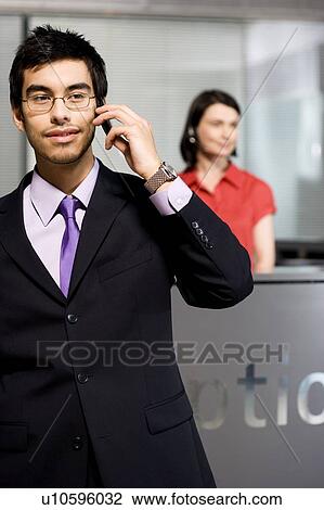 Businessman making a call on his mobile phone at reception View Large Photo Image Stock Image - Businessman making a call on his mobile phone at reception. Fotosearch