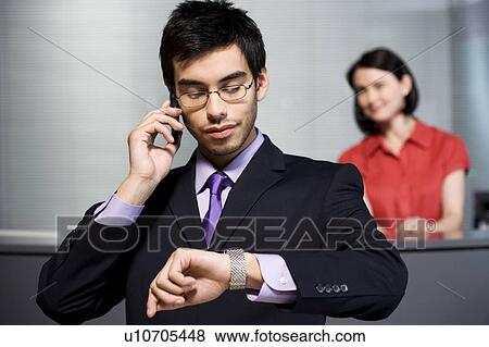 Stock Photo - Businessman making a call on his mobile phone at reception. Fotosearch