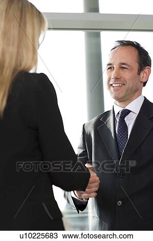 Stock Image - Businessman shaking hands with female client or colleague. Fotosearch