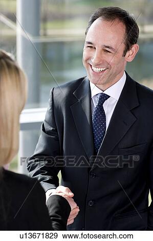 Businessman shaking hands with female client or colleague View Large Photo Image Stock Photo - Businessman shaking hands with female client or colleague. Fotosearch