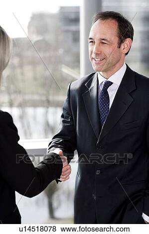 Stock Photo - Businessman shaking hands with female client or colleague. Fotosearch