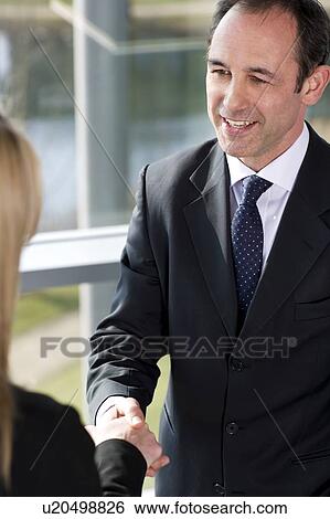 Businessman shaking hands with female client or colleague View Large Photo Image Stock Photograph - Businessman shaking hands with female client or colleague. Fotosearch