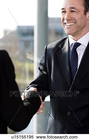 Stock Photography - Businessman shaking hands with female client or colleague. Fotosearch